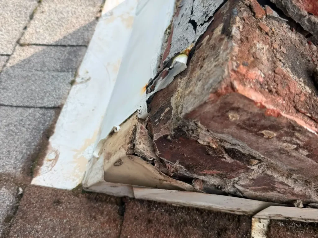 Failed chimney flashing and eroded mortar at the roof line where water has been entering