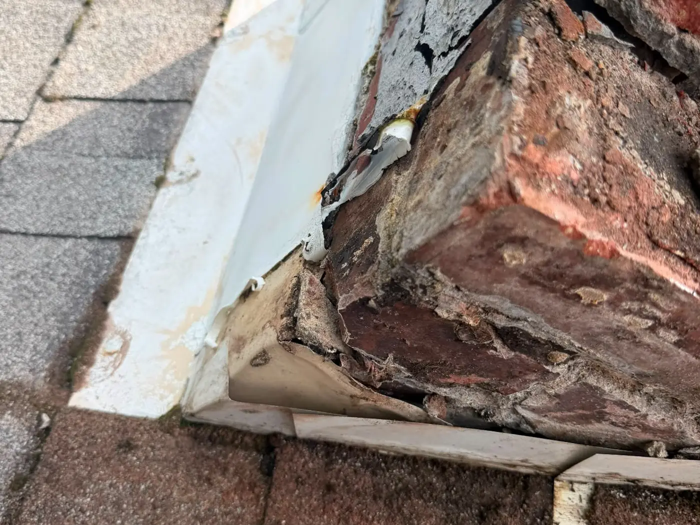 Failed chimney flashing and eroded mortar at the roof line where water has been entering