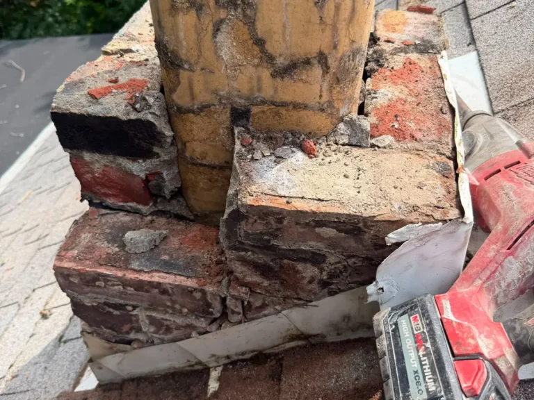 Partially rebuilt brick chimney with fresh masonry and tools on the roof mid repair