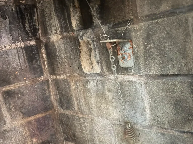 Close view of weathered mortar joints in a soot stained masonry chimney wall before tuckpointing