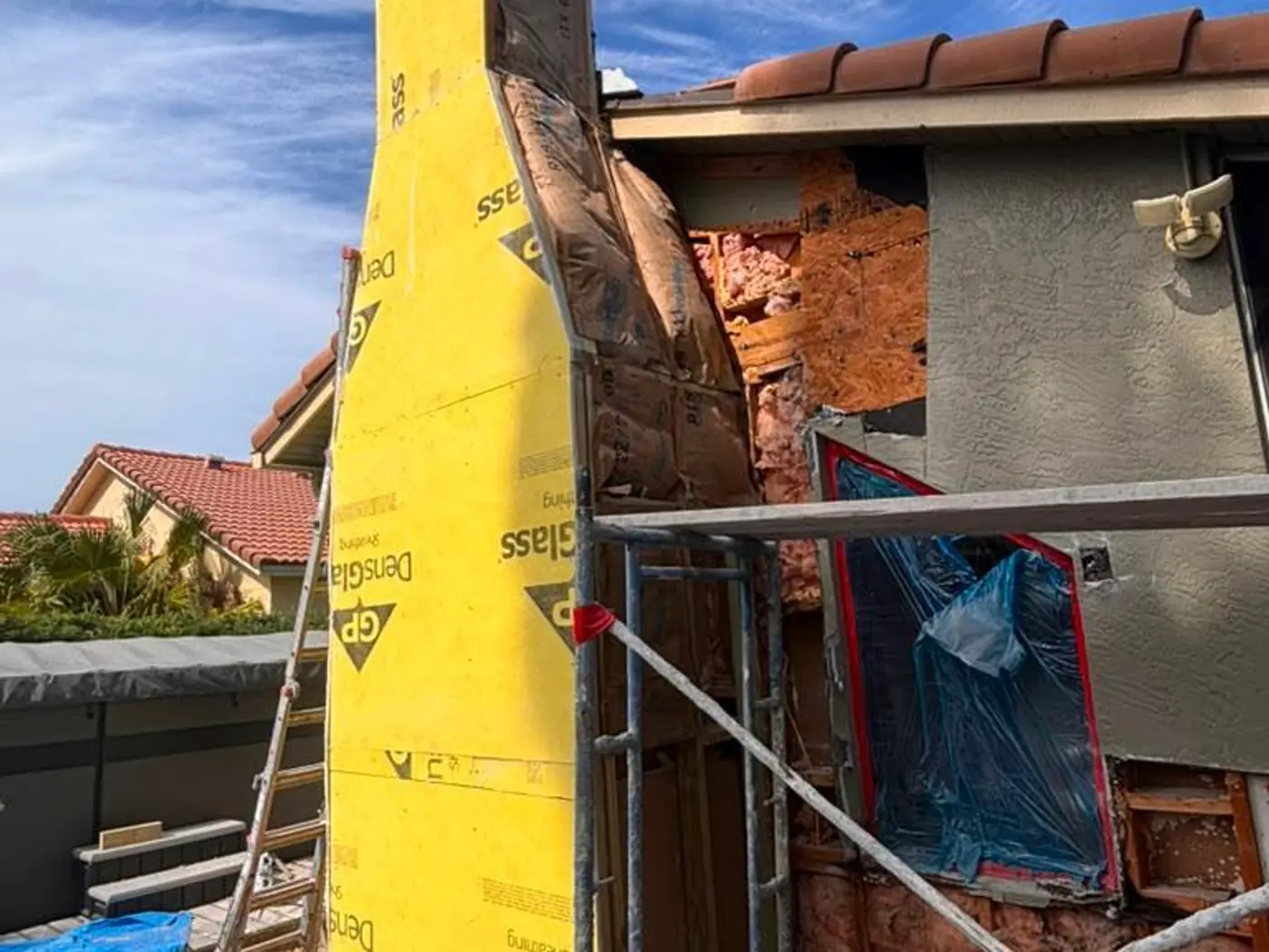 Chimney stripped back to the framing and wrapped for rebuilding with scaffolding in place