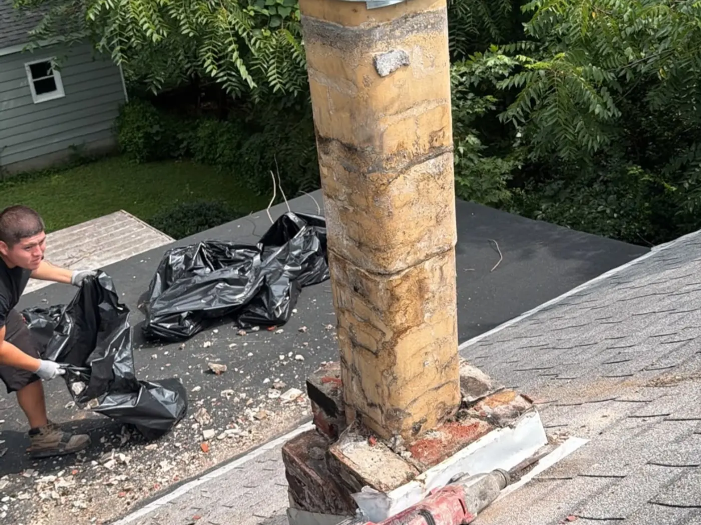 Chimney technician on a roof fitting a new metal liner and cap to a rebuilt brick chimney