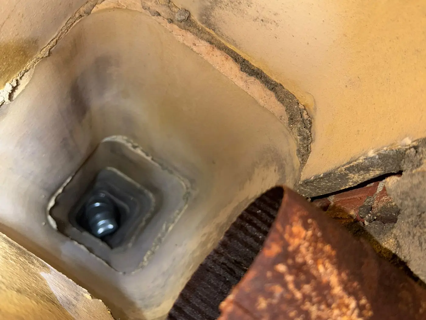 Rusted and deteriorated flue liner connection inside a chimney showing failed metal and mortar