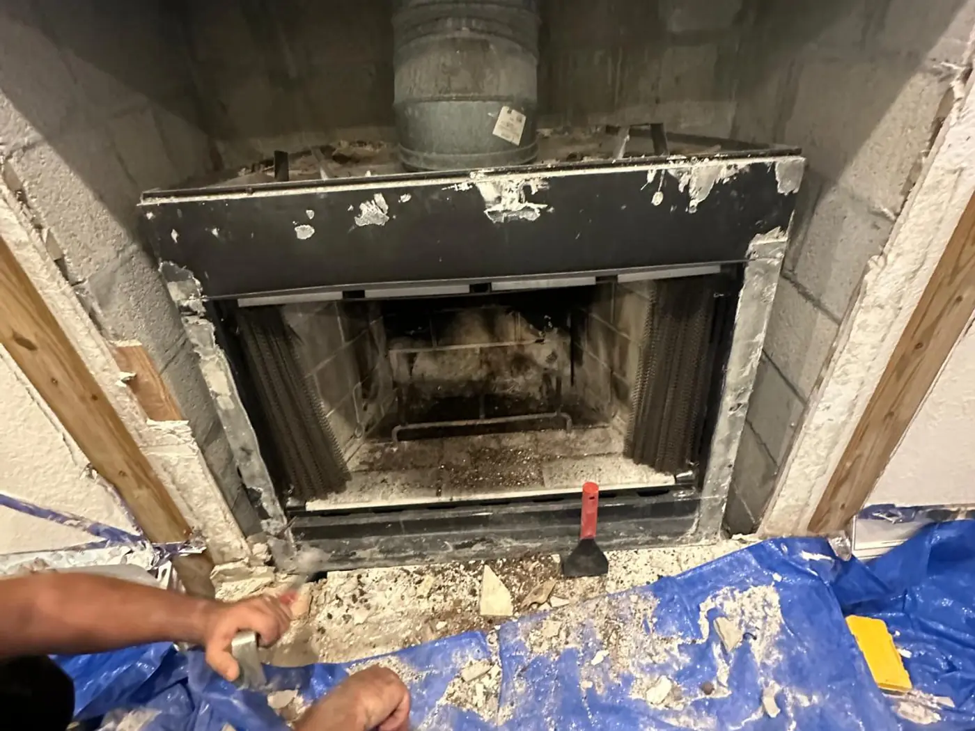 Technician working inside an opened firebox with the damper and smoke chamber exposed