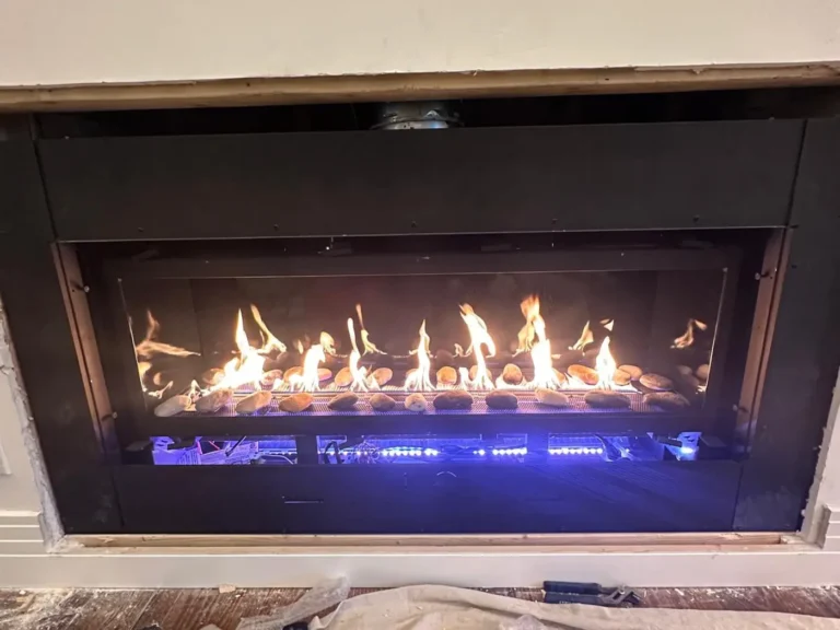 Newly installed linear gas fireplace burning in a living room during final fitting