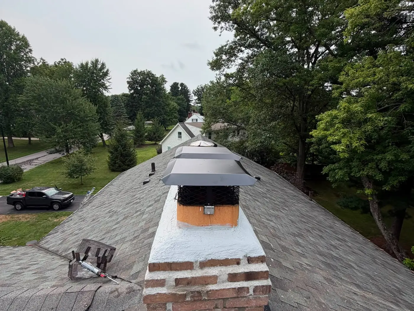 Rebuilt chimney crown finished in fresh mortar seen along a residential roofline